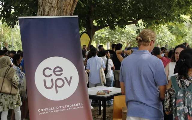 Pancarta del CEUPV junto a un grupo numeroso de estudiantes bajo los árboles, en la jornada de bienvenida