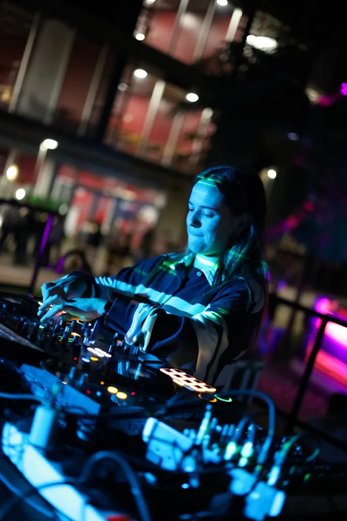 Una DJ mezcla en la controladora, iluminada con luces azules