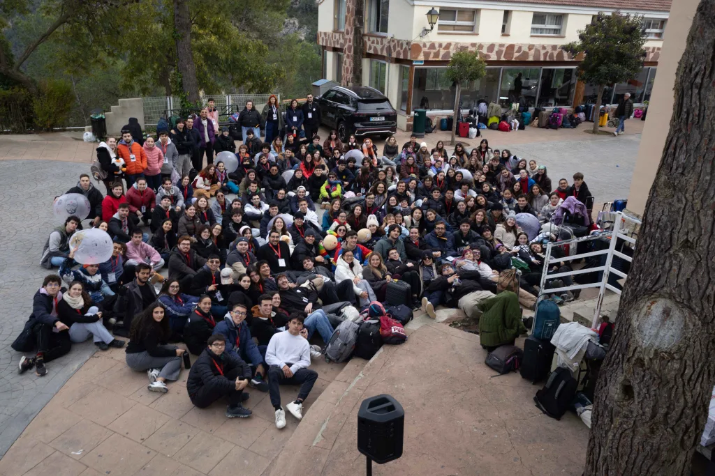Foto de grupo de los participantes de las jornadas, sentados en la explanada delante del edificio, con las maletas al lado