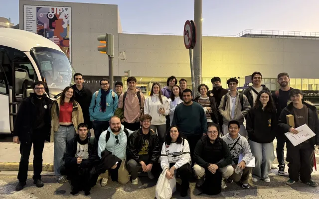 Foto de grupo de los participantes junto al autobús, delante de un edificio de la UPV, al atardecer